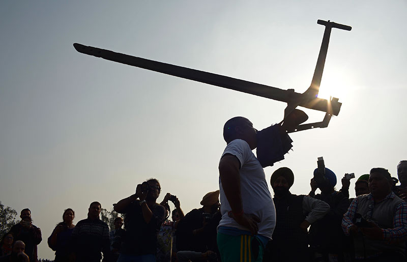 A man lifts a plough with his mouth. A man lifts a plough with his mouth.