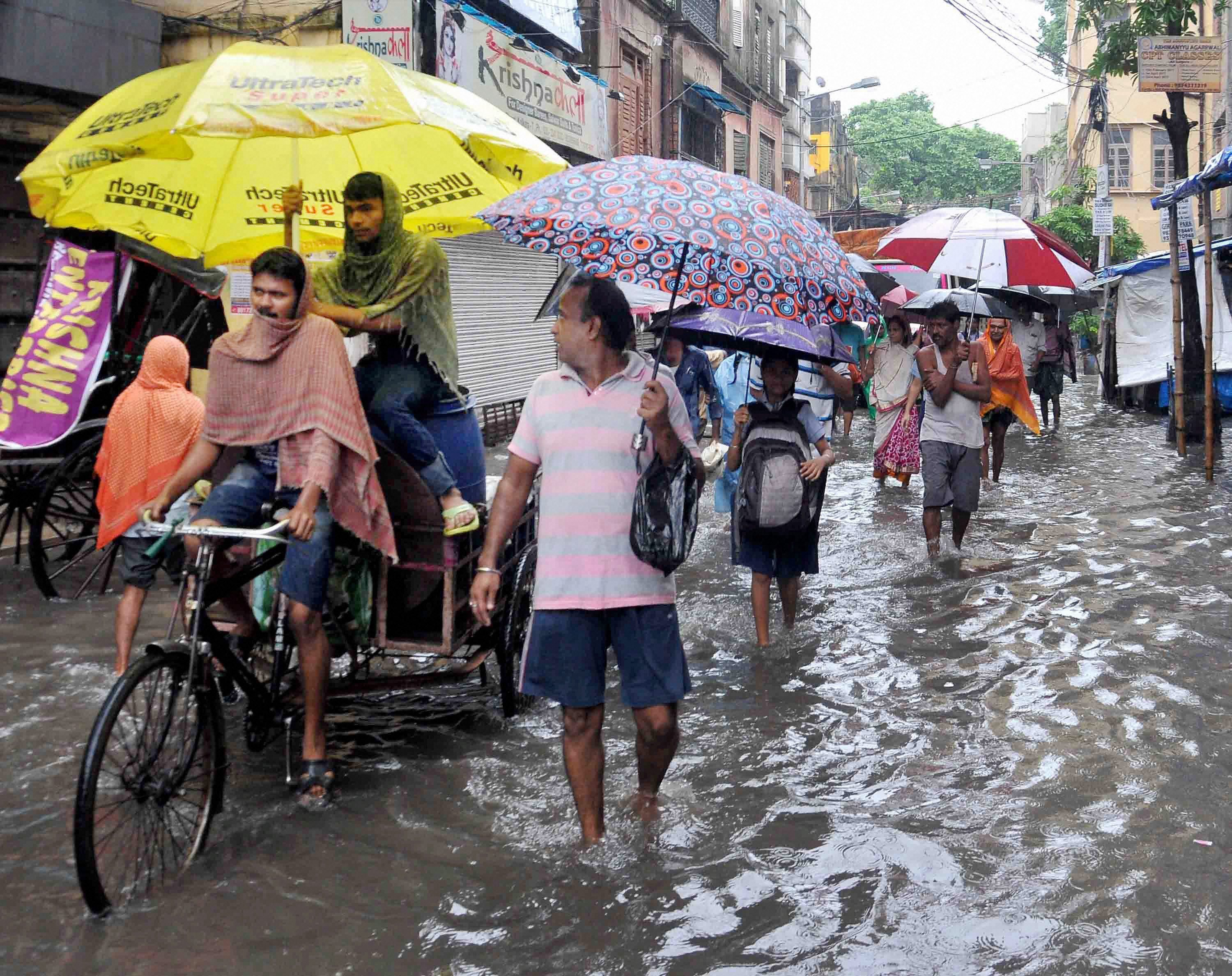 People walk through ankle-deep water in a street in Kolkata. (Credit: PTI) People walk through ankle-deep water in a street in Kolkata. (Credit: PTI)