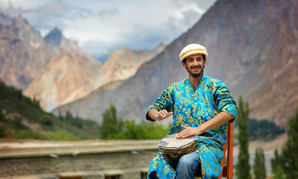 A student happily plays the drums. A student happily plays the drums.