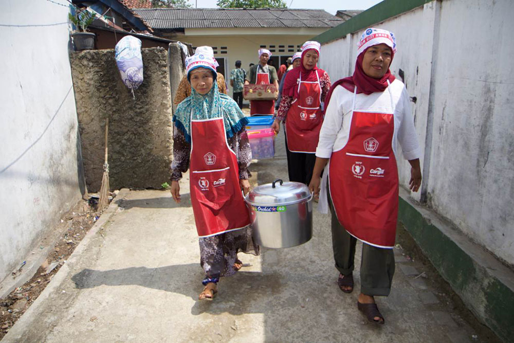A group of mothers whose children study at a small primary school in Serang, some 60 km outside Indonesia’s capital Jakarta, carry cooked meals from the small kitchen to the school, a short walk away, May 19, 2017. Photo credit: Thin Lei Win/Thomson Reuters Foundation A group of mothers whose children study at a small primary school in Serang, some 60 km outside Indonesia’s capital Jakarta, carry cooked meals from the small kitchen to the school, a short walk away, May 19, 2017. Photo credit: Thin Lei Win/Thomson Reuters Foundation