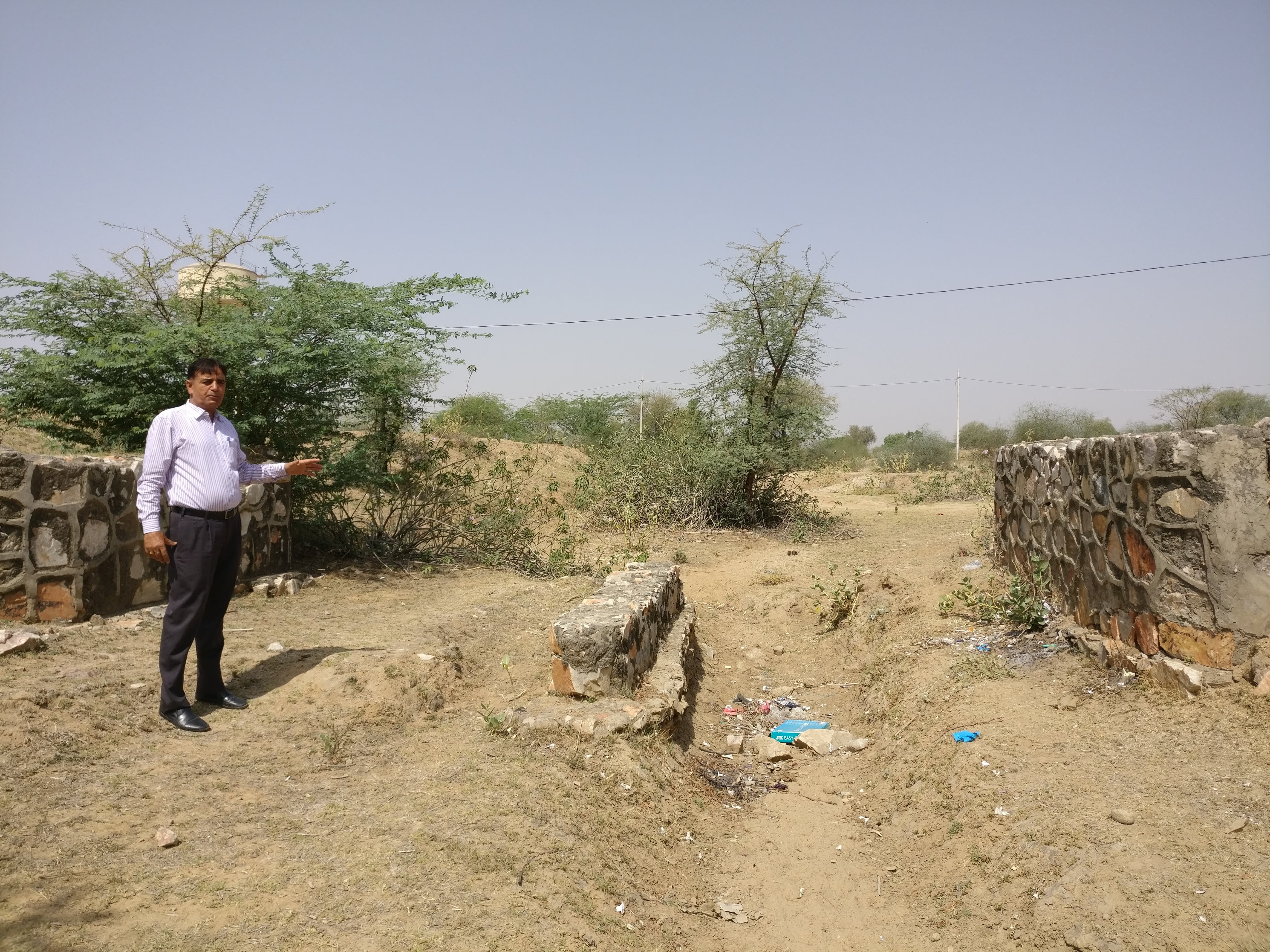 Vishnu Punya, a teacher at Adarsh senior school in Pipla, points to the remains of a bridge over a channel that diverted rainwater from the school premises and into a nearby pond. Now the area floods during the rains. Vishnu Punya, a teacher at Adarsh senior school in Pipla, points to the remains of a bridge over a channel that diverted rainwater from the school premises and into a nearby pond. Now the area floods during the rains.