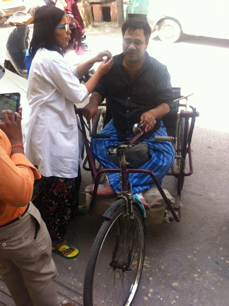 A doctor examines Munna Singh, a physically handicapped person, outside the Krishna Nagar mohalla clinic. (Photo: Menaka Rao) A doctor examines Munna Singh, a physically handicapped person, outside the Krishna Nagar mohalla clinic. (Photo: Menaka Rao)