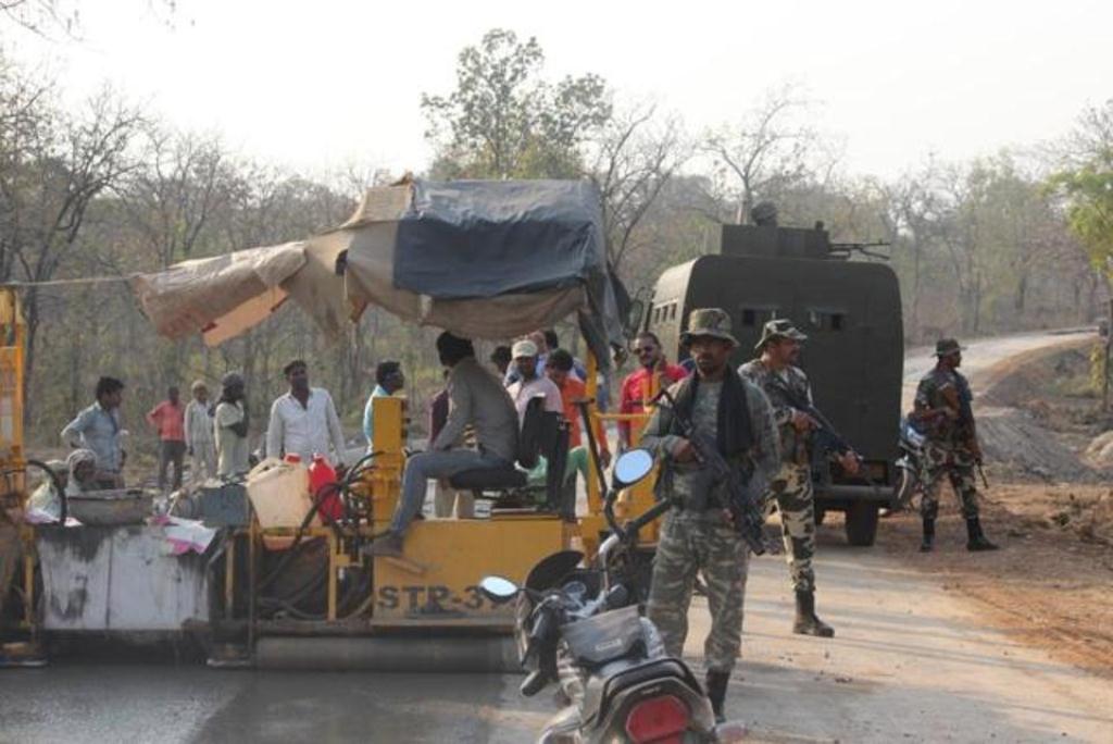 Security personnel stand guard as a road is laid in Bastar. Image credit: HT Security personnel stand guard as a road is laid in Bastar. Image credit: HT