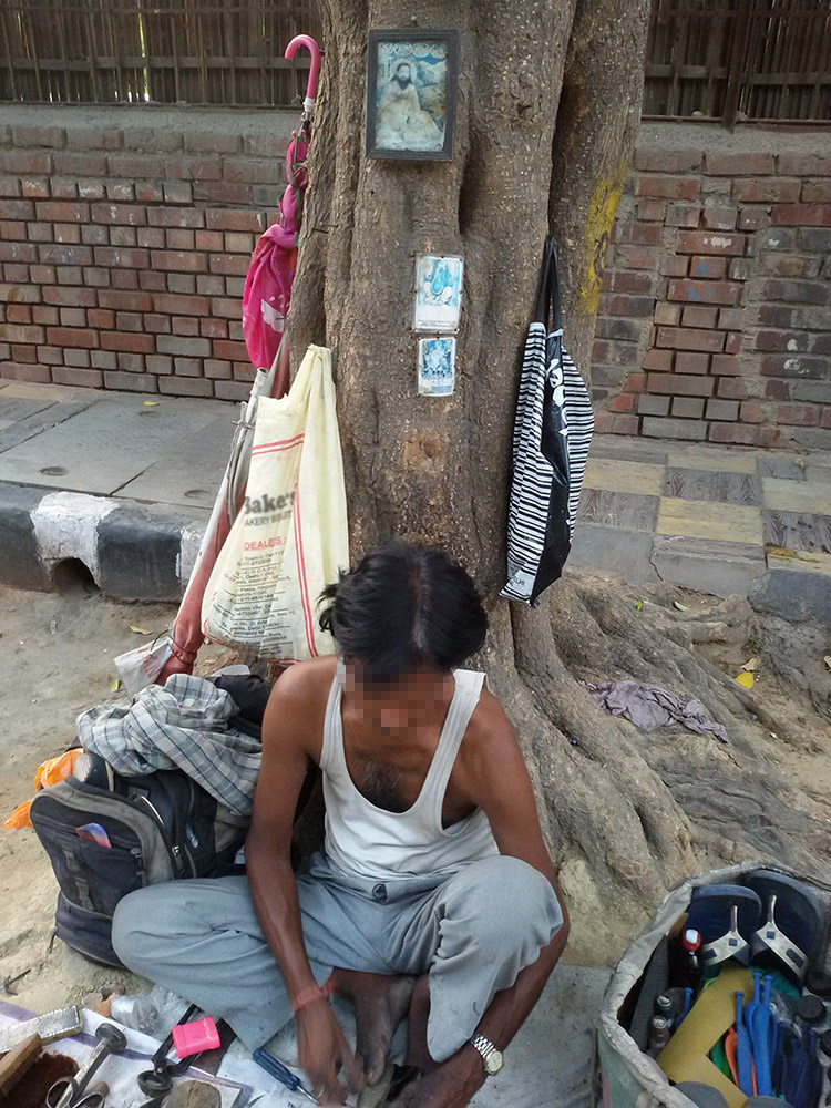 A Ravidassia at work on a pavement in Rohini, Delhi. A framed portrait of Ravidas hangs on the tree behind him. Photo credit: Santosh Kumar Singh A Ravidassia at work on a pavement in Rohini, Delhi. A framed portrait of Ravidas hangs on the tree behind him. Photo credit: Santosh Kumar Singh