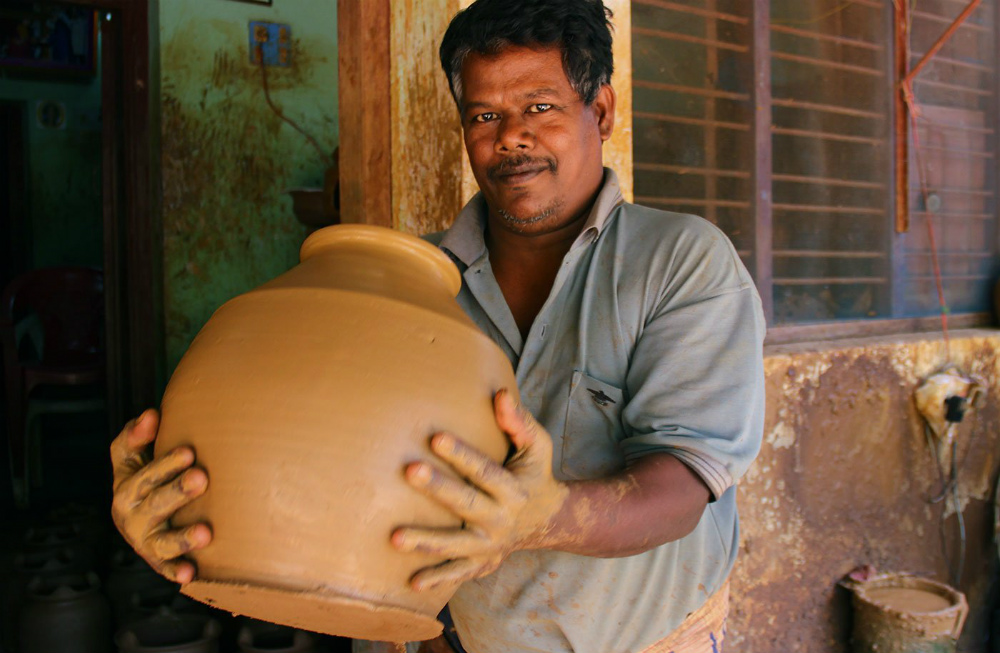 Ramesh lifts the raw clay plot from the wheel and carries it indoors. Ramesh lifts the raw clay plot from the wheel and carries it indoors.