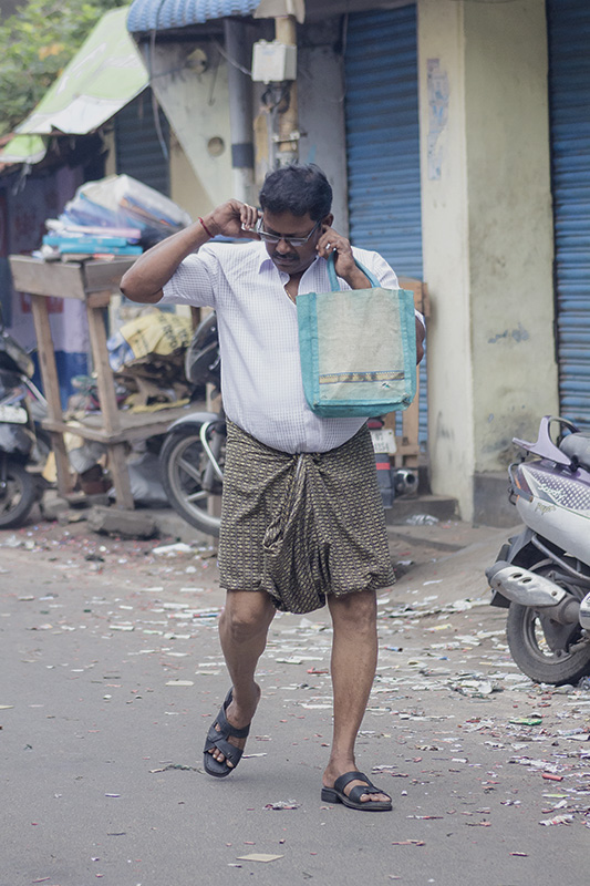 Man walks down a street covering and shielding his ears from a loud noise as a cracker goes off nearby. Photo credit: Shuchi Kapoor/Chennai Man walks down a street covering and shielding his ears from a loud noise as a cracker goes off nearby. Photo credit: Shuchi Kapoor/Chennai