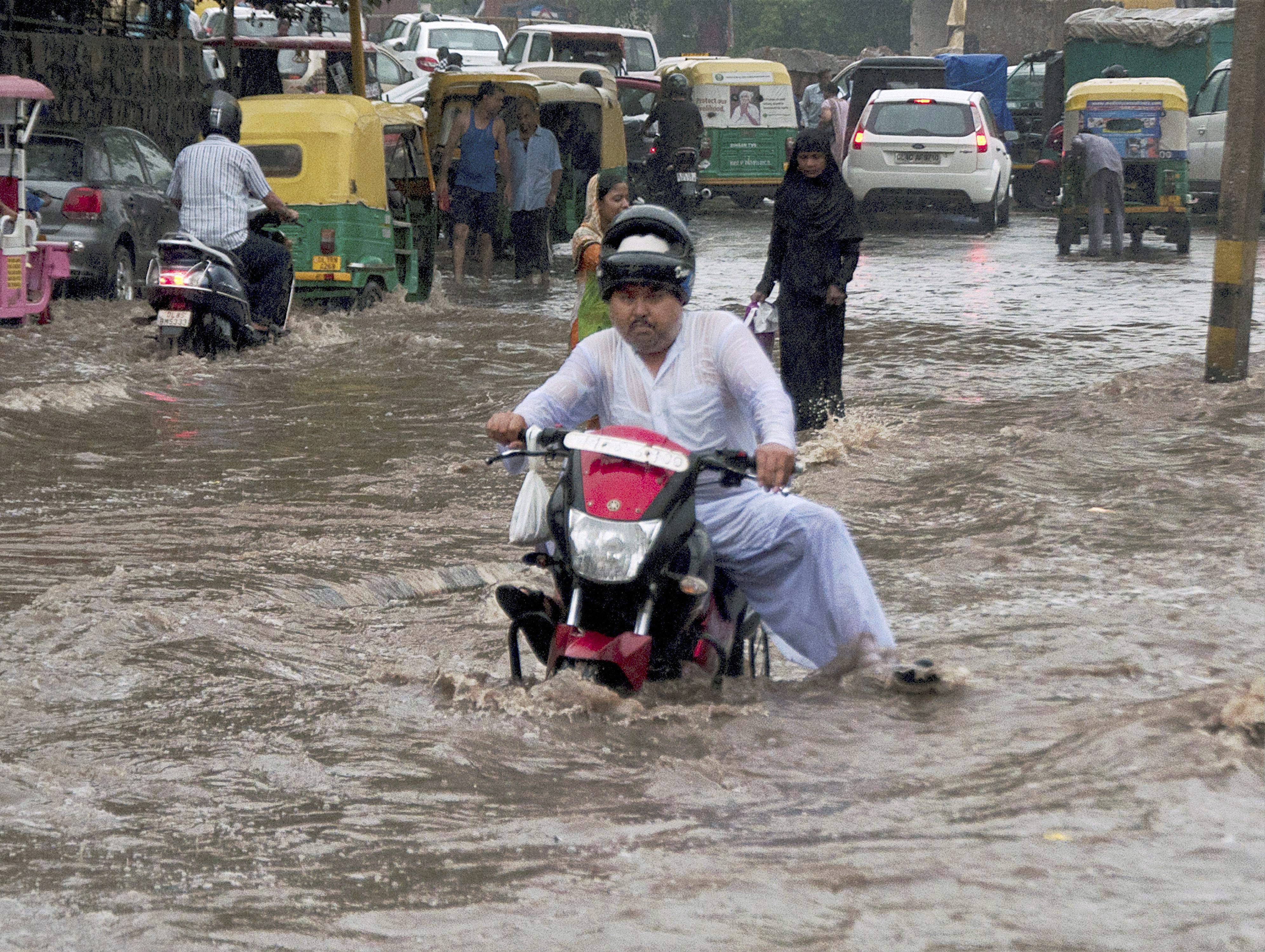 People wade through knee-high water as rain leads to flooding in Delhi. (Credit: PTI) People wade through knee-high water as rain leads to flooding in Delhi. (Credit: PTI)