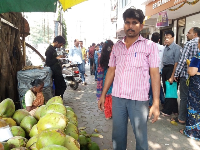 Mohammed Aziz at his coconut stall, right outside a bank with a long queue. Mohammed Aziz at his coconut stall, right outside a bank with a long queue.