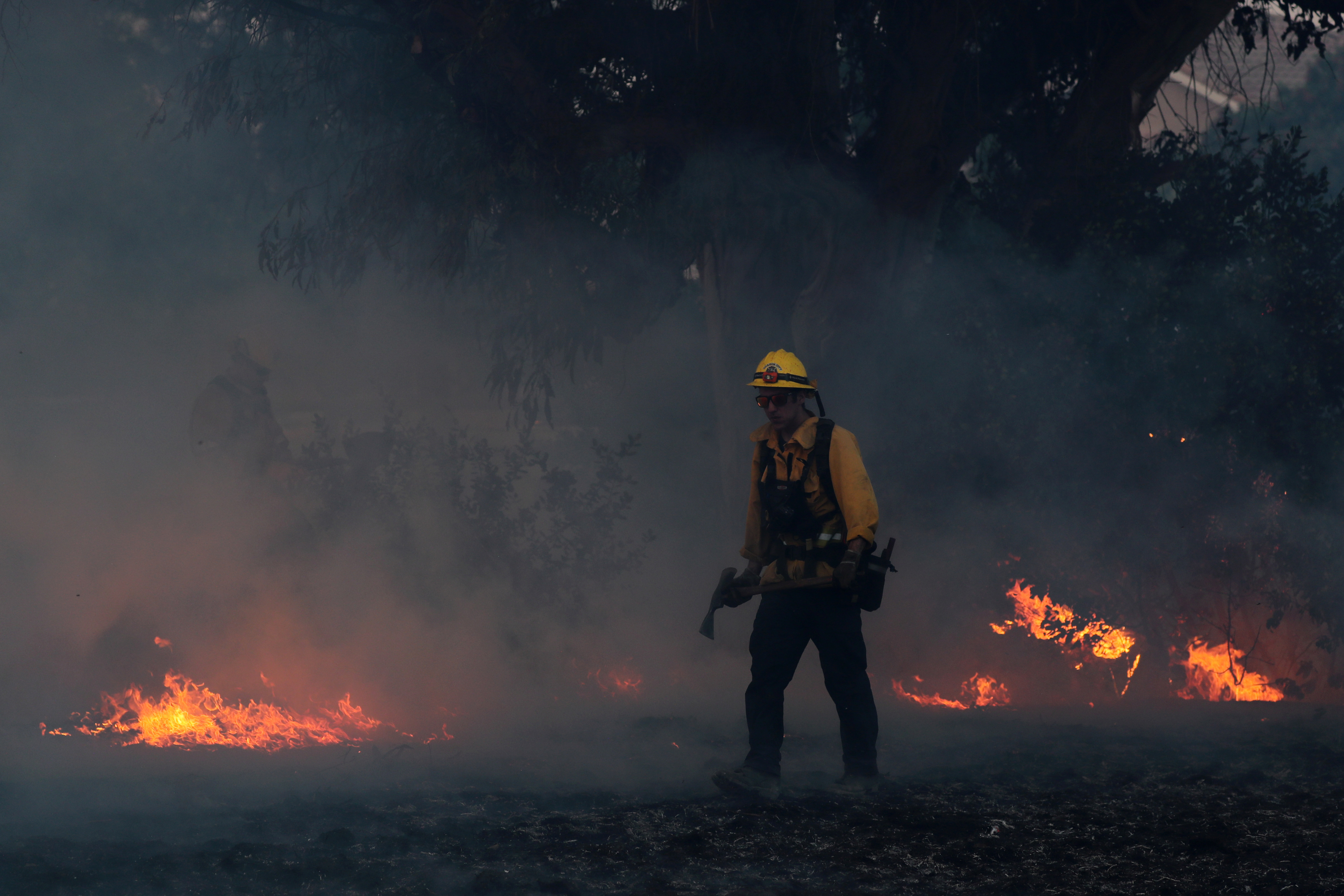 A firefighter works to put out hot spots during the wind-driven wildfire. (Photo Credit: Mike Blake/Reuters) A firefighter works to put out hot spots during the wind-driven wildfire. (Photo Credit: Mike Blake/Reuters)