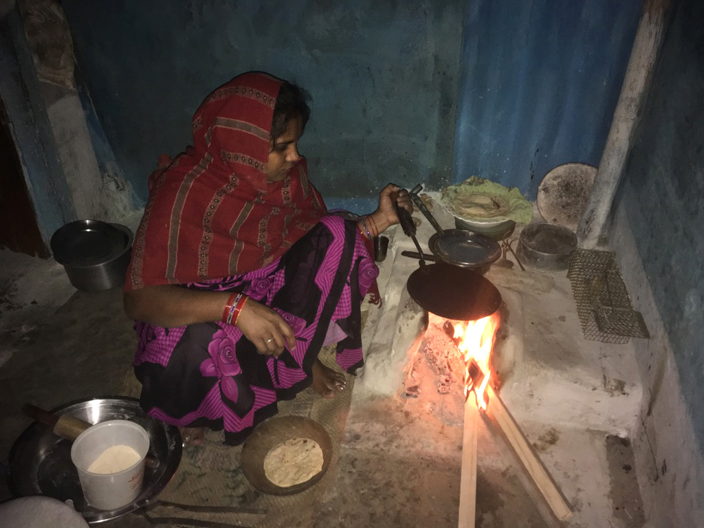 An Andhera Gher resident using wood blocks to fuel her earthen stove to cook dinner. Photo credit: Menaka Rao. An Andhera Gher resident using wood blocks to fuel her earthen stove to cook dinner. Photo credit: Menaka Rao.