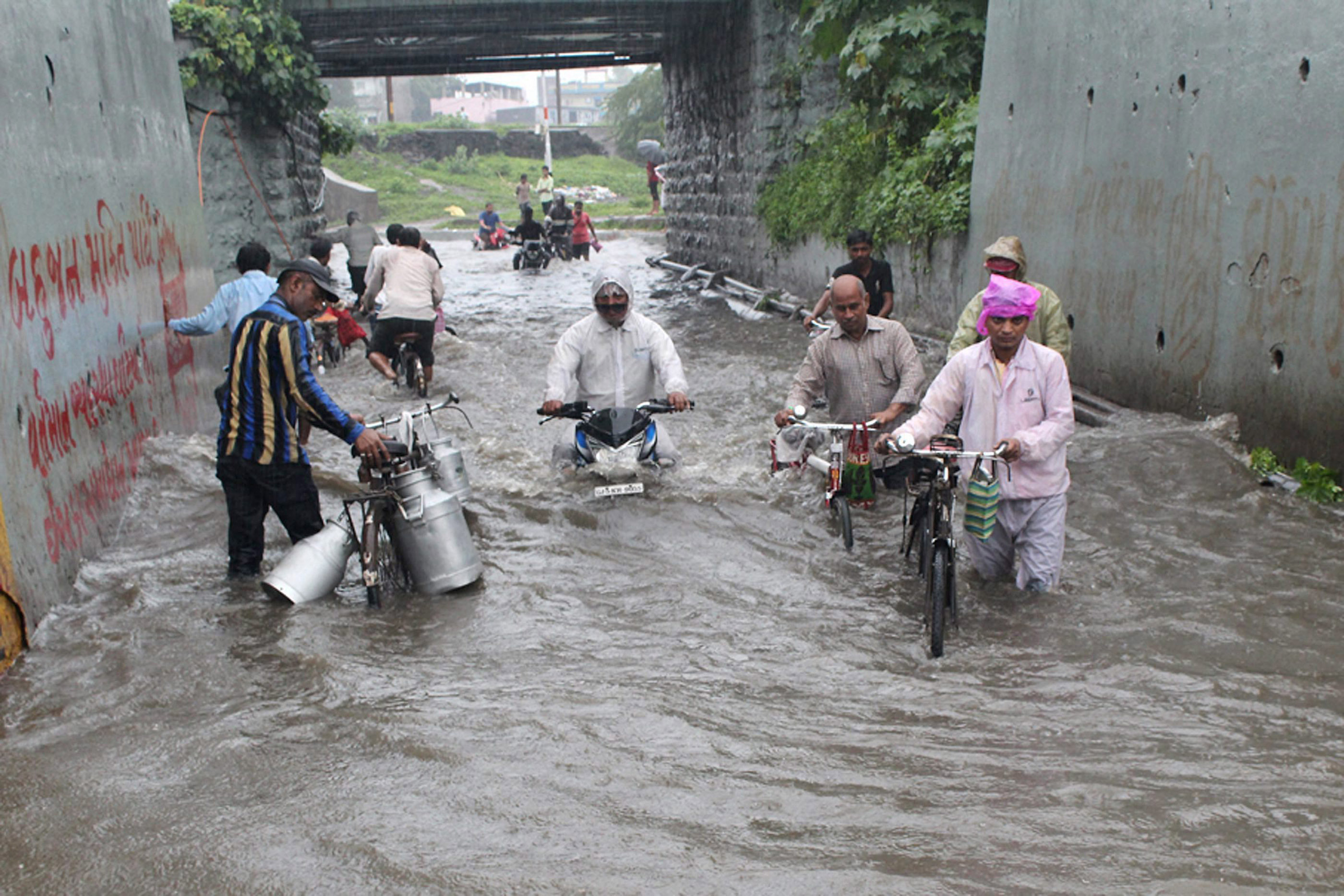 People struggle through knee-deep water in a street in Surat. (Credit: PTI) People struggle through knee-deep water in a street in Surat. (Credit: PTI)
