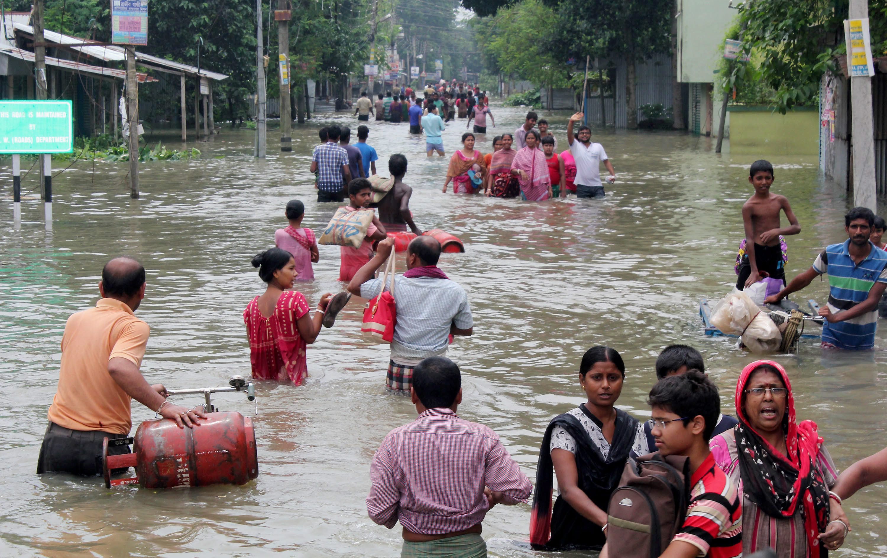 People wade through a flooded road in Bularghat in West Bengal's South Dinajpur district. (Credit: PTI) People wade through a flooded road in Bularghat in West Bengal's South Dinajpur district. (Credit: PTI)