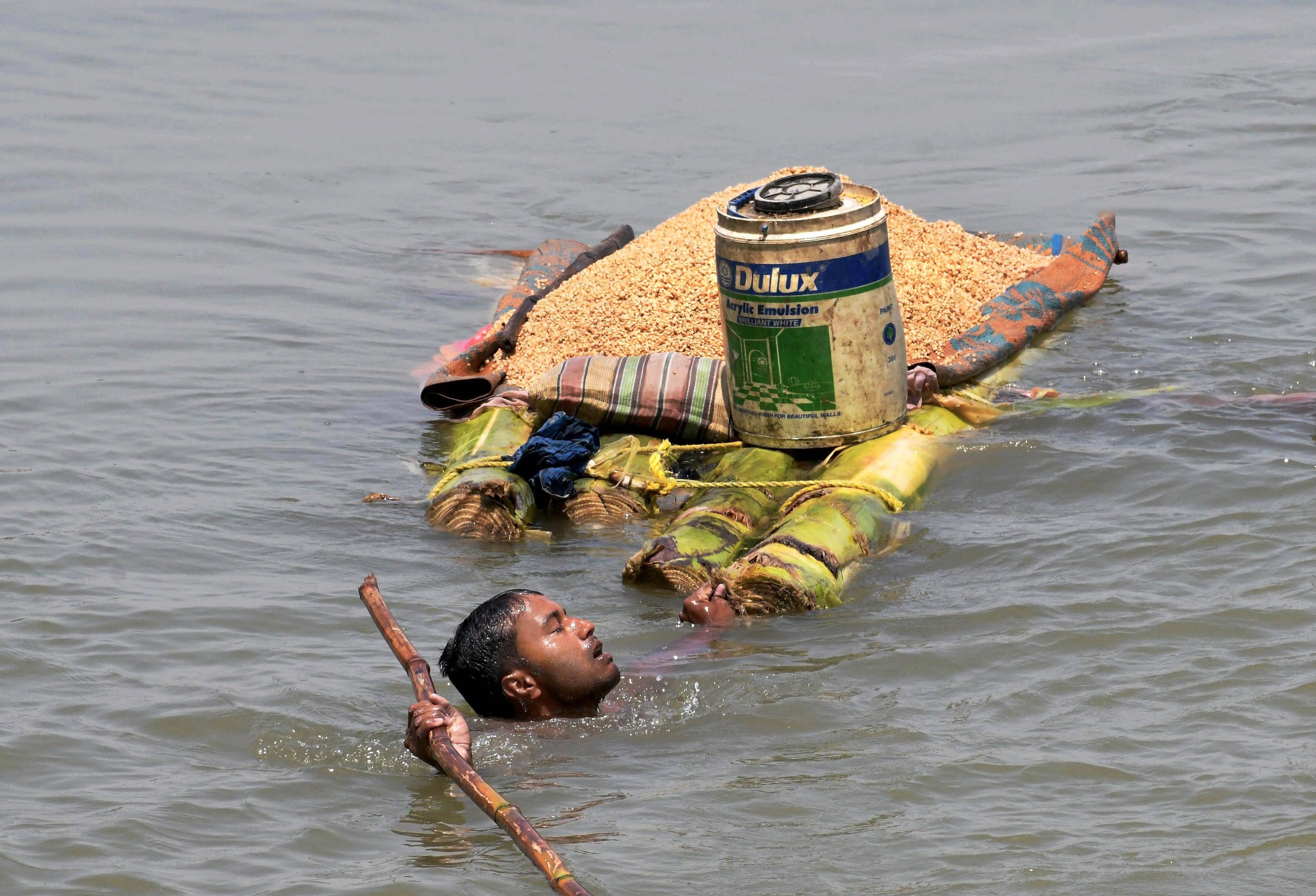 A man carries grains on a banana raft in Araria district of Bihar on Monday. PTI Photo A man carries grains on a banana raft in Araria district of Bihar on Monday. PTI Photo