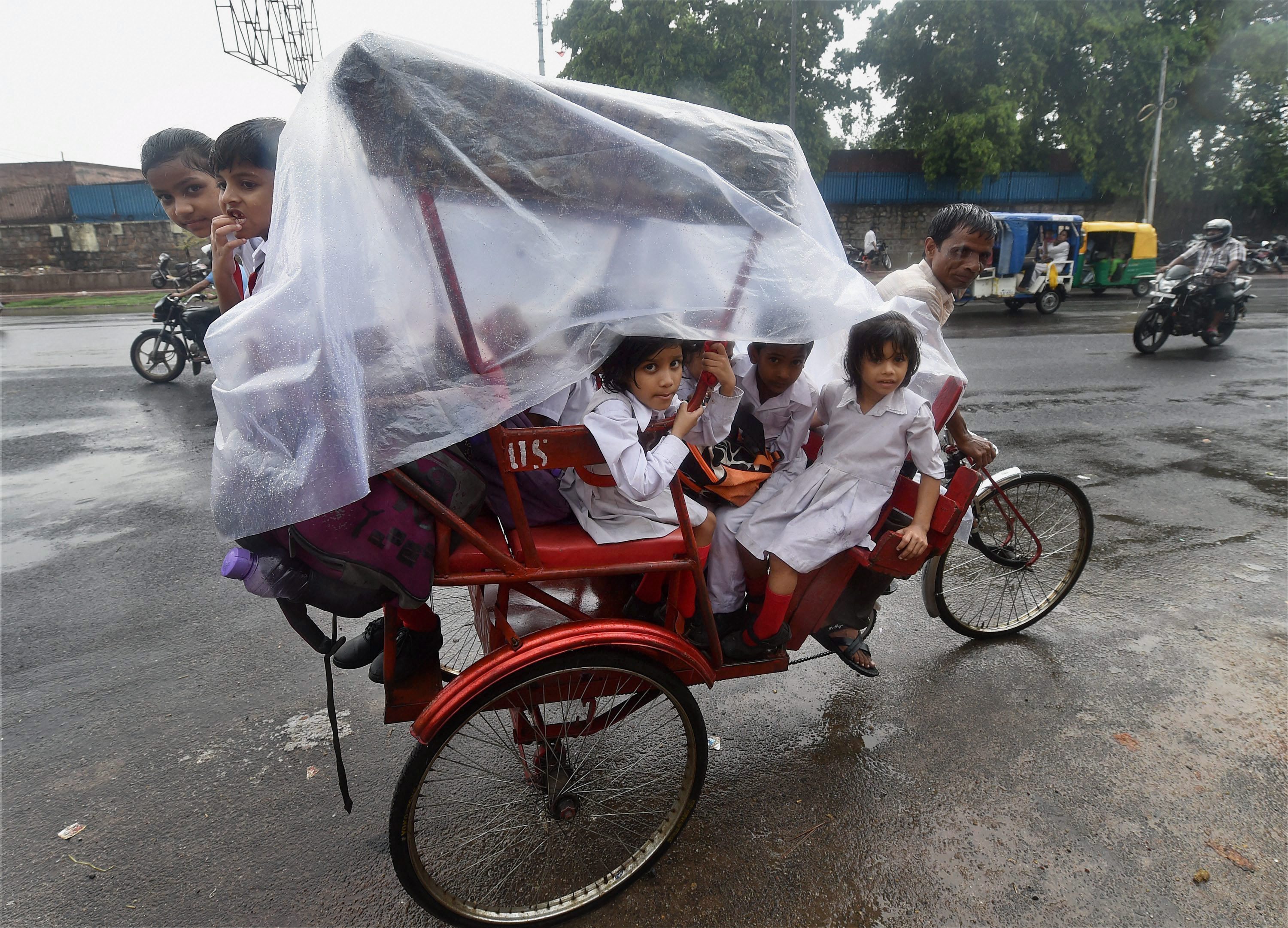 Schoolchildren take shelter in a cycle rickshaw as it rains in Delhi. (Credit: PTI) Schoolchildren take shelter in a cycle rickshaw as it rains in Delhi. (Credit: PTI)