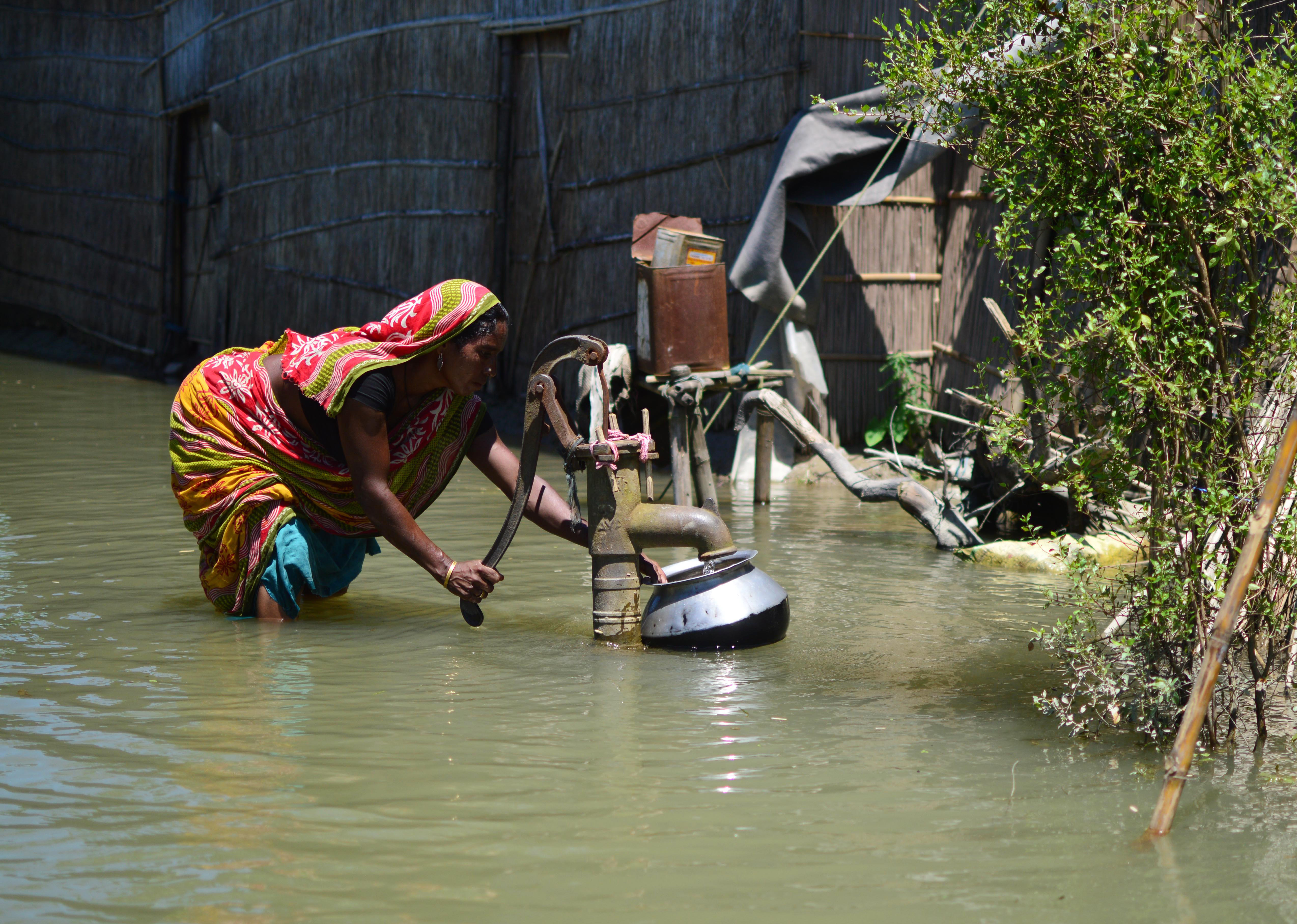 A woman uses a hand pump knee deep in water in Assam's Kamrup district. (Credit: AFP) A woman uses a hand pump knee deep in water in Assam's Kamrup district. (Credit: AFP)