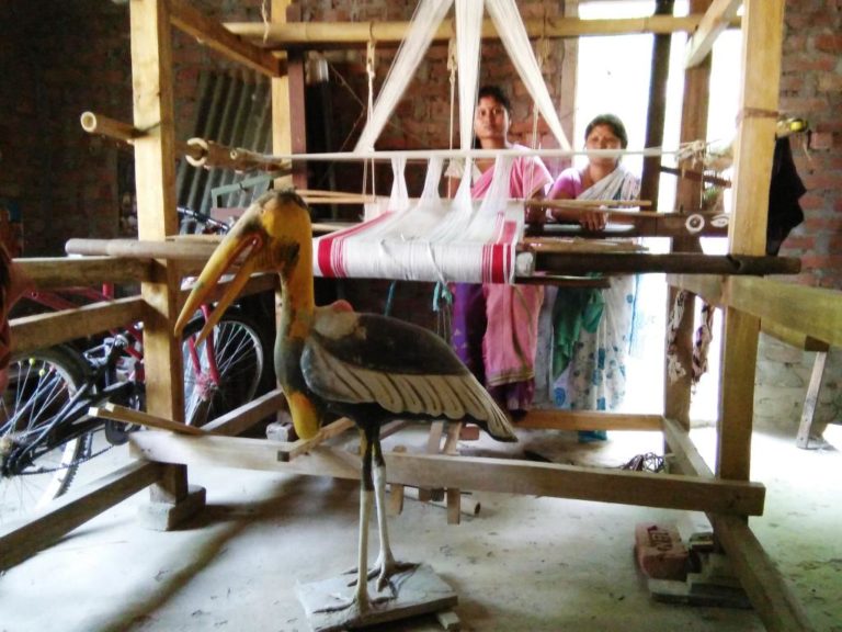 Members of the self help weaving group with Greater Adjutant statue and handloom donated by the government. Image Credit: Purnima Barman Members of the self help weaving group with Greater Adjutant statue and handloom donated by the government. Image Credit: Purnima Barman