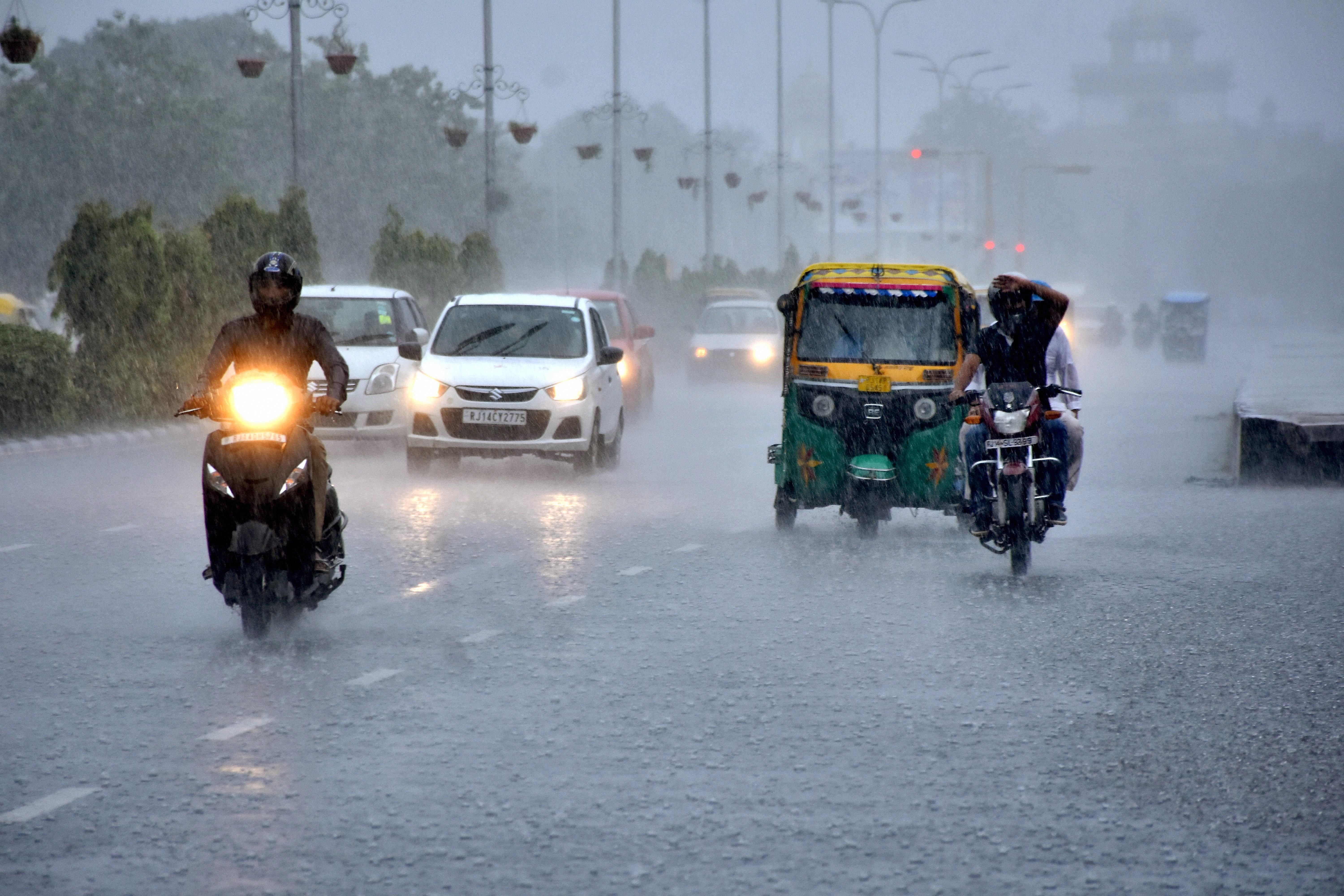 Low visibility because of heavy rainfall forces commuters to drive with their headlights on during the day. (Credit: PTI) Low visibility because of heavy rainfall forces commuters to drive with their headlights on during the day. (Credit: PTI)