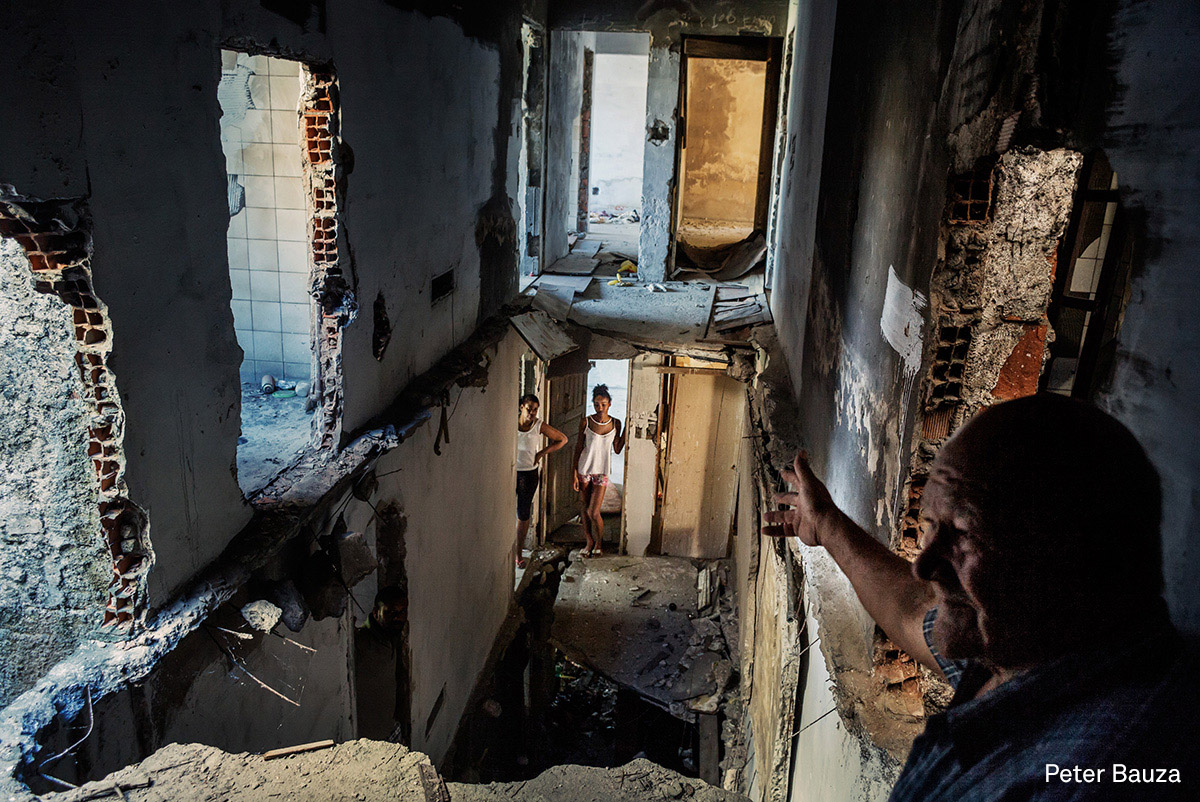 Contemporary Issues, third prize (stories) | Copacabana Palace: A pastor, who also lives in the occupied buildings, explains all the construction problems. A couple of weeks ago, the hall floors from a building crashed down at night. Fortunately everybody was sleeping and nothing serious happened. Most of the buildings are exposed to corrosion, July 2015. (Peter Bauza) Contemporary Issues, third prize (stories) | Copacabana Palace: A pastor, who also lives in the occupied buildings, explains all the construction problems. A couple of weeks ago, the hall floors from a building crashed down at night. Fortunately everybody was sleeping and nothing serious happened. Most of the buildings are exposed to corrosion, July 2015. (Peter Bauza)