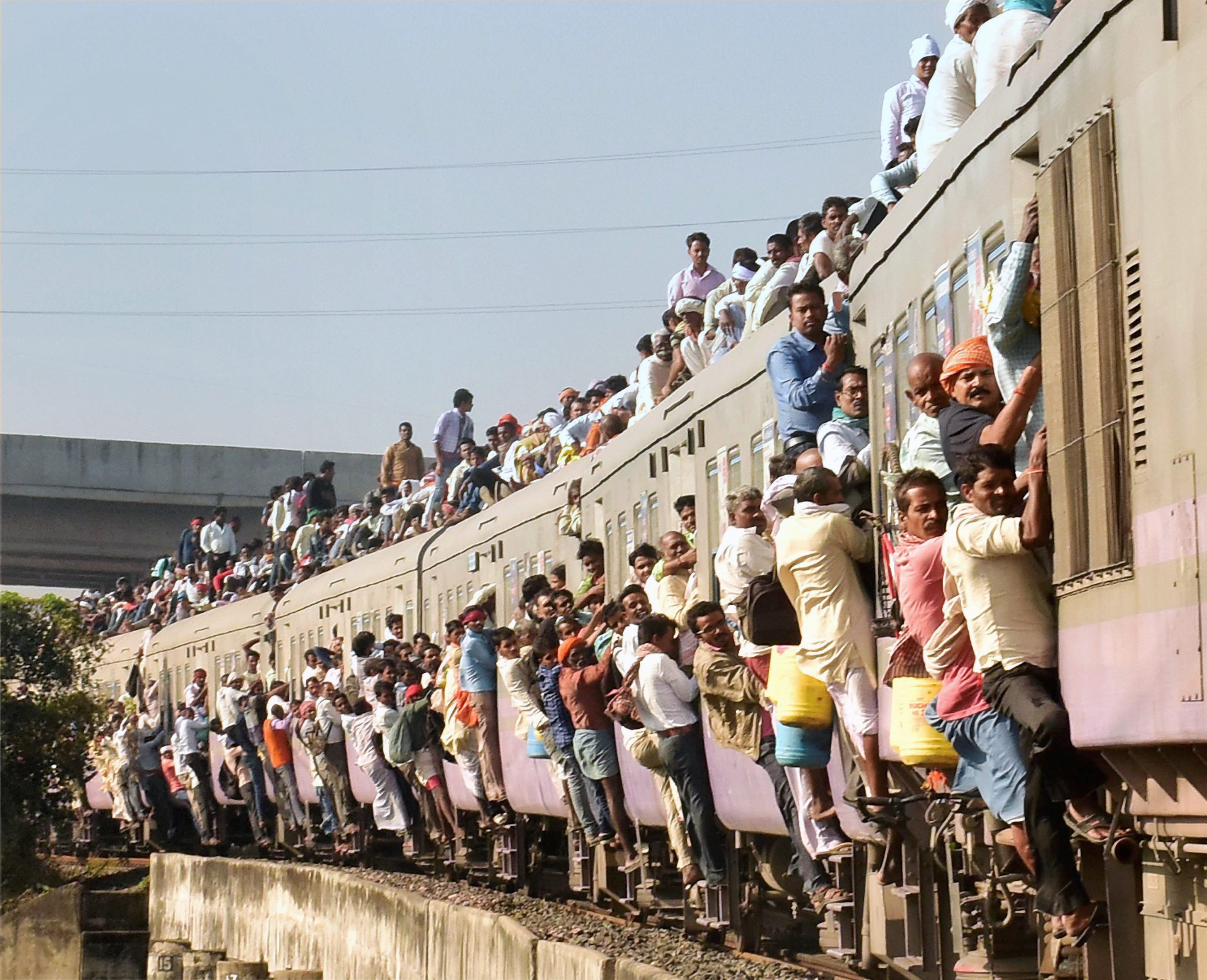 Passengers hang out of a train heading to Patna in Bihar, overcrowded by the Kartik Purnima rush . (Credit: PTI) Passengers hang out of a train heading to Patna in Bihar, overcrowded by the Kartik Purnima rush . (Credit: PTI)