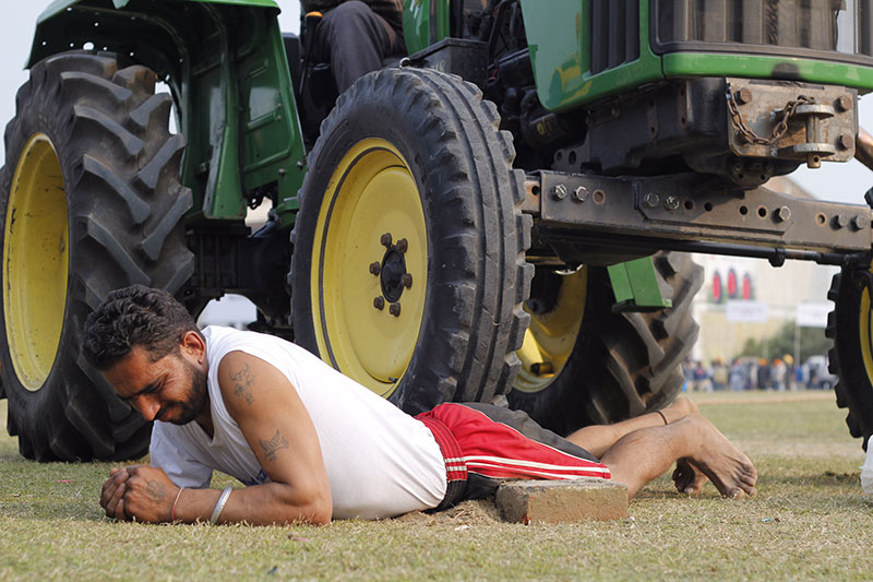 A man displays his toughness by letting a tractor run over him. A man displays his toughness by letting a tractor run over him.