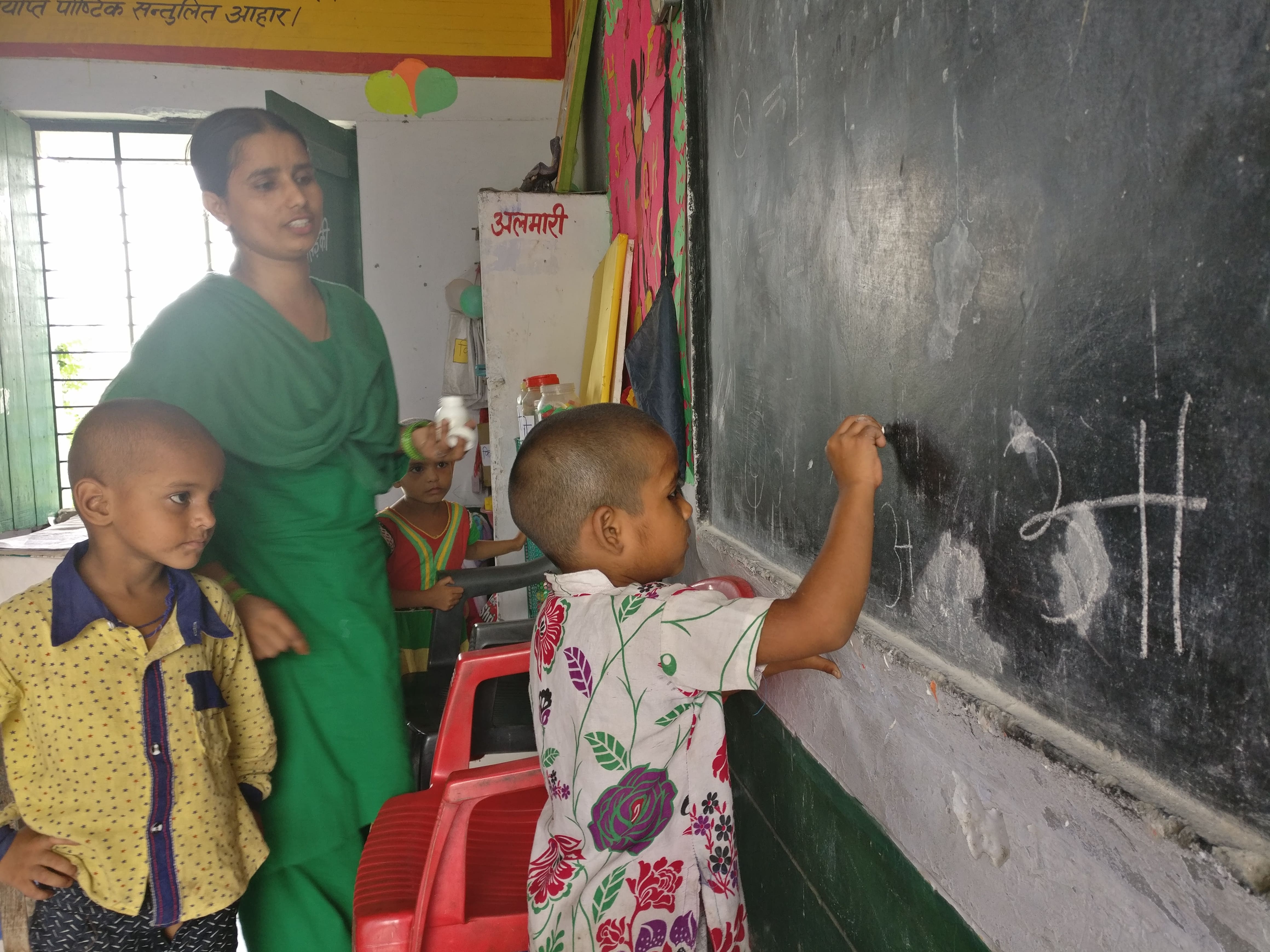 Anganwadi worker Shabana Parveen watches Sophia, 5, write. Sophia only knows the first few letters of the Hindi alphabet. Photo credit: Shreya Roy Chowdhury Anganwadi worker Shabana Parveen watches Sophia, 5, write. Sophia only knows the first few letters of the Hindi alphabet. Photo credit: Shreya Roy Chowdhury