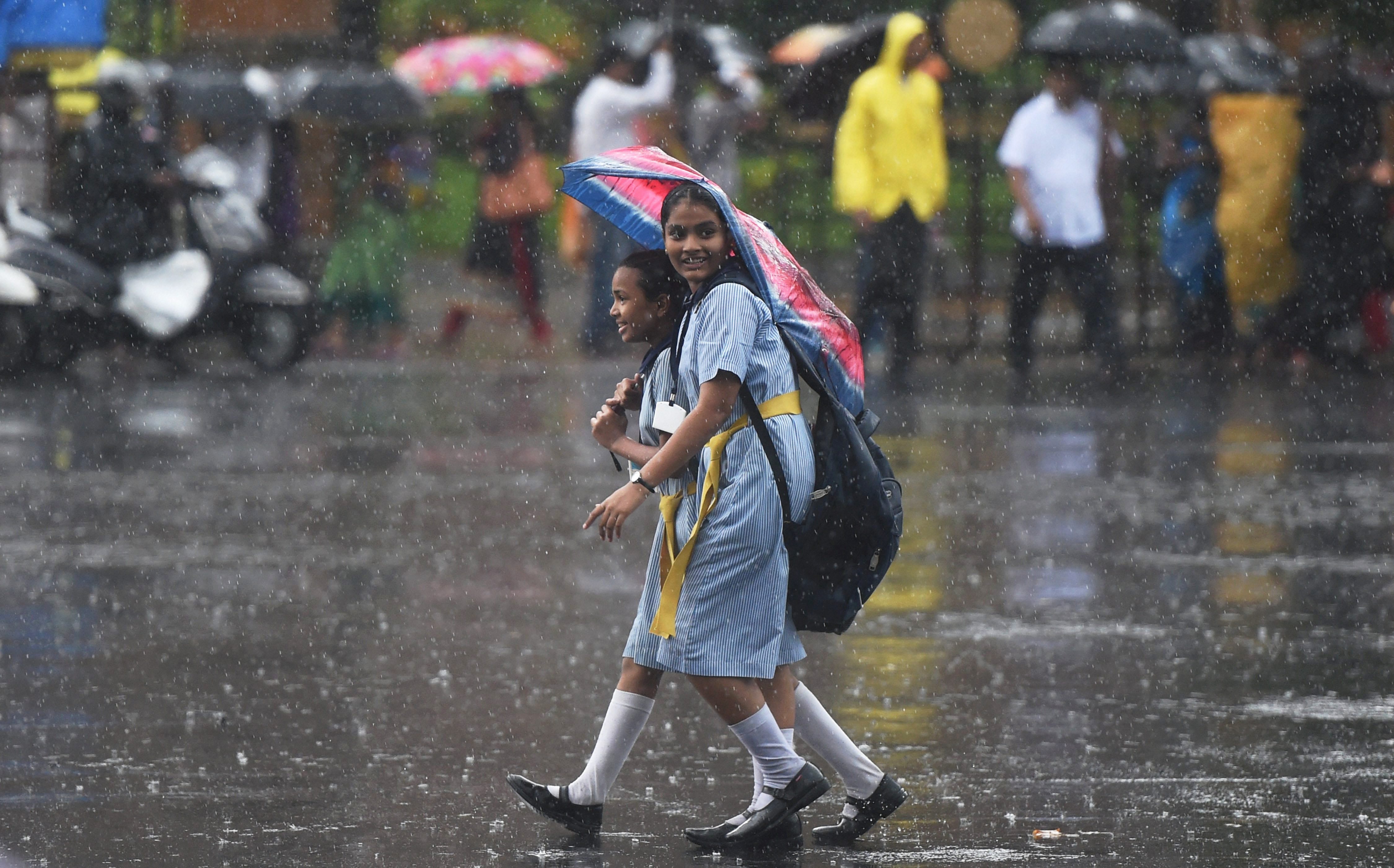 School students walk through a downpour in the city (Photo credit: PTI) School students walk through a downpour in the city (Photo credit: PTI)
