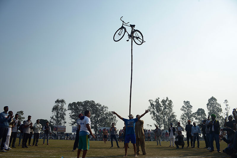A competitor balances a bicycle on his mouth. A competitor balances a bicycle on his mouth.
