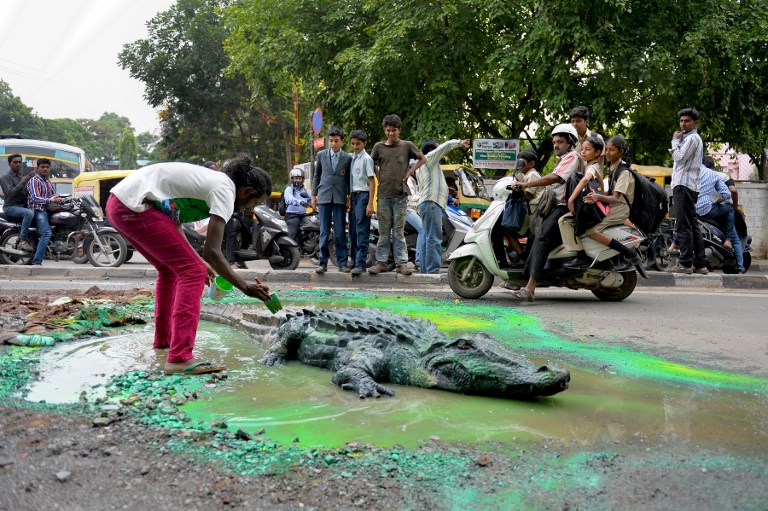 Baadal Nanjundaswamy paints and places a life-size model of a crocodile into a huge water-logged pothole in Bengaluru Sultanpalya traffic junction on June 18, 2015. (Credit: Manjunath Kiran/AFP) Baadal Nanjundaswamy paints and places a life-size model of a crocodile into a huge water-logged pothole in Bengaluru Sultanpalya traffic junction on June 18, 2015. (Credit: Manjunath Kiran/AFP)